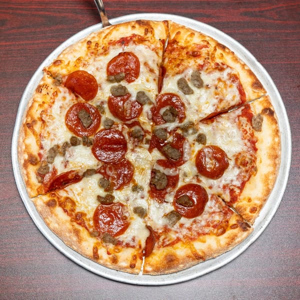 A freshly baked pepperoni and sausage pizza on a metal pan, sliced and ready to serve.