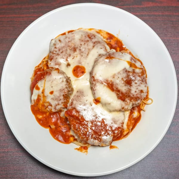 Rincon Italian Grill's baked ziti with melted mozzarella cheese and rich red sauce on a white plate.